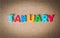 Colorful wooden word JANUARY on cork board with selective focus