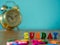 Colorful wooden word SUNDAY on wooden table and vintage alarm clock