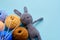 Colorful yarn clews with gray stuffed bunny and needles on the blue background. Concept of amigurumi toy making, handcrafting,