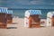 Colorfuled striped roofed chairs on sandy beach in Travemunde. A blurred couple sitting on beach in background. Lubeck