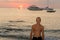 Colorfull portrait of handsome topless man looking up and smiling during sunset at the beach.
