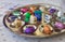 Colorfully wrapped assortment of pralines presented on golden plate or dish on table with shallow depth of field