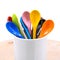 Colors ceramics spoon in mug on wooden backdrops. Colorful concept