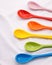 Colors ceramics spoon on white fabric background. Colorful concept