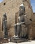 Colossal seated statue and a standing statue of Rameses II at the 1st Pylon, the main entrance for  the Luxor Temple.