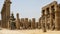 Colossal statue of seated Ramesses II and standing statues between papyrus-bud columns in the Ramesses II Court, Luxor Temple.