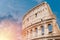 Colosseum or Coliseum ancient ruins background blue sky Rome, Italy, view from below, stone arches and sunrays