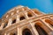 Colosseum or Coliseum ancient ruins background blue sky Rome, Italy, view from below, stone arches and sunrays