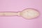 Colostrum powder, in a wooden spoon, on a pink background