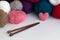 Colour balls of yarn and knitting needles on white table. with pink heart of wool yarn