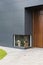 A colour photograph of a white dog and a brown dog waiting infront of a low window at a house with timber and aluminium cladding