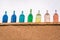 Coloured glass bottles standing on the muddy wall