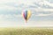 Coloured hot-air balloon flying over a rural landscape