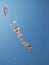 Coloured kites flying at wind in the blue sky guided by childrens