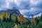 Colourful autumn picture of yellow and orange coloured trees in front of an alpine mountain in the italian Dolomites