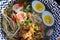 Colourful bowl of mushroom and pulled pork ramen with soft boiled egg and sesame seeds