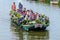 Colourful canal parade of flower and vegetables decorated boats with cheerful dressed up singing and dancing people
