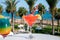 Colourful cold Strawberry daiquiri and Rainbow Paradise cocktails drinks served in glasses at outdoor cafe overlooking blue sea