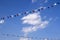 Colourful decorative triangular flags under blue sky with clouds