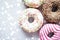 Colourful donuts on marble table with glowing snow, winter holiday food background