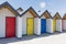Colourful doors of blue, yellow and red, with each one being numbered individually, of white beach houses on a sunny day