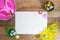 Colourful easter background flatlay on wooden table with white paper space for words. Pink hat, rabbit, chick, easter eggs in nest