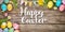 Colourful Easter background with Happy Easter Text decorated eggs and spring flowers, on a rustic wooden background