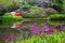 Colourful flowers and shrubs grow around the lake at the John Lewis Longstock Park Water Garden, Hampshire UK