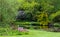 Colourful flowers and shrubs grow around the lake at the John Lewis Longstock Park Water Garden, Hampshire UK