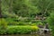 Colourful flowers and shrubs grow around the lake at the John Lewis Longstock Park Water Garden, Hampshire UK