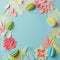 Colourful handmade tropical paper flowers and leggs on blue pastel background with copyspace, seasonal easter wreath, summer