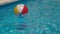 Colourful inflatable beach ball floating in shiny blue swimming pool water