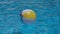 Colourful inflatable beach ball floating in shiny swimming pool in blue water