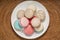 Colourful macarons in white plate on wooden table, Sweet makaron from almond flour and cream.