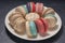 Colourful macarons in white plate on wooden table, Sweet makaron from almond flour and cream.