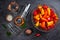 Colourful  mini bell peppers in glass bowl  and empty glass jars ready to be marinated on dark background, top view