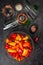 Colourful  mini bell peppers in glass bowl  and empty glass jars ready to be marinated on dark background, top view, vertical