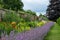 Colourful mixed herbaceous border at Oxburgh Hall, Norfolk UK. By the path are low growing clumps of purple Catmint.