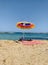 Colourful parasol on the beach. Single umbrella and towel on empty sandy beach and beautiful water of Mediterranean sea