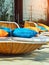 Colourful pillows on modern daybed. Brown rattan loungers with orange and blue pillows hanging with rope by relaxing terrace.