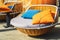 Colourful pillows on modern daybed. Brown rattan loungers with orange and blue pillows hanging with rope by relaxing terrace.