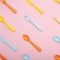 Colourful plastic tableware : forks, knifes and spoons on pink background.