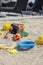 Colourful plastic toys with various shapes and kinds left unattended on a sand beach.