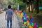 Colourful rainbow pinwheel in the park with people walking along the pathway.