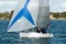 Colourful sailing dingy with blue and white spinnaker being navigated by junior sailors