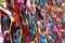 Colourful strings of ribbon tied to a fence.