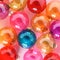 Colourful translucent glass Christmas baubles on pink background. Creative decoration.