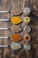Colourful various spices in spoons and in glass jars on a wooden table. Top view. Cooking background