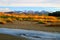 Colourful wild autumn landscape of river, nature bushes and mountains on background