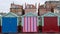 Colourful wooden beach huts on the sea front in Hove, Sussex, UK with blocks of flats behind.